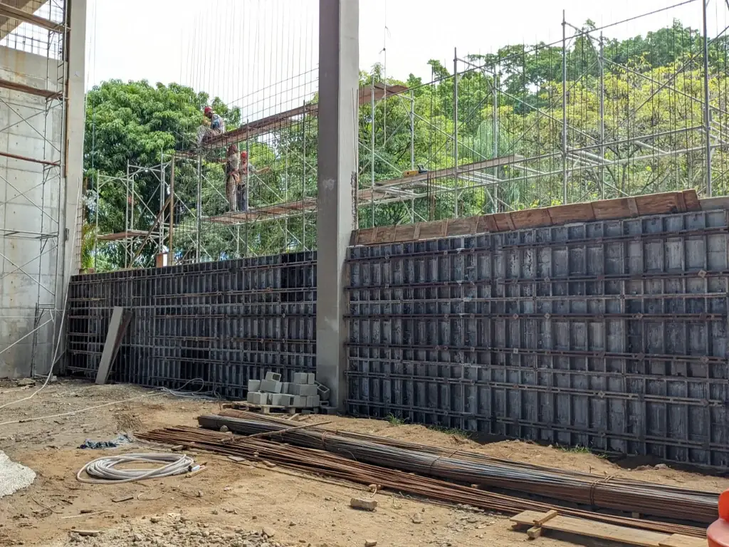 Muro alto com formas escoradas em obra, exemplo de escoramento em terreno inclinado